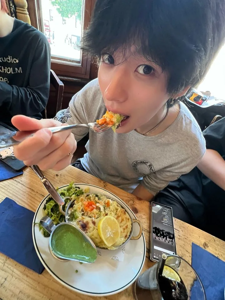 A close-up at a restaurant, leaning toward the camera with a fork.