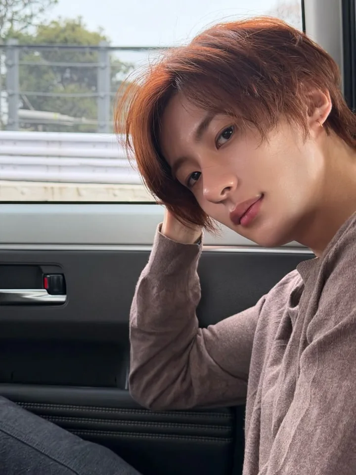 A portrait by a car window with a hand resting beside the face.
