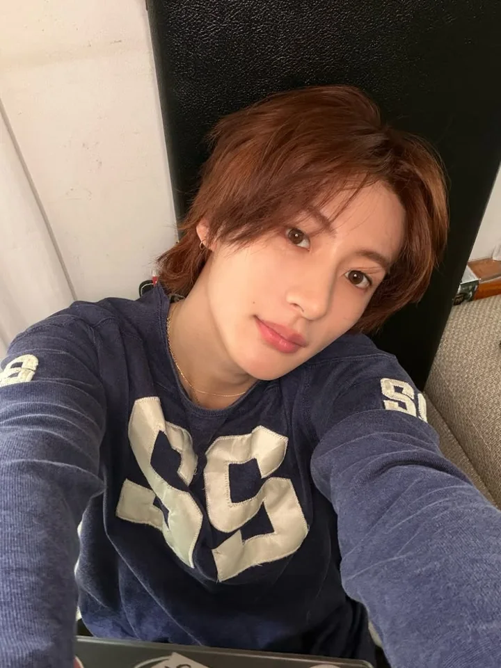 A selfie in a navy sweater against a dark seat.